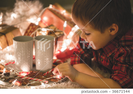 Boy laying under christmas tree with chocolate 36671544