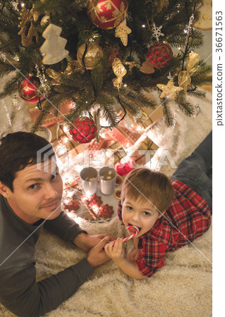 Father and son laying under christmas tree. 36671563