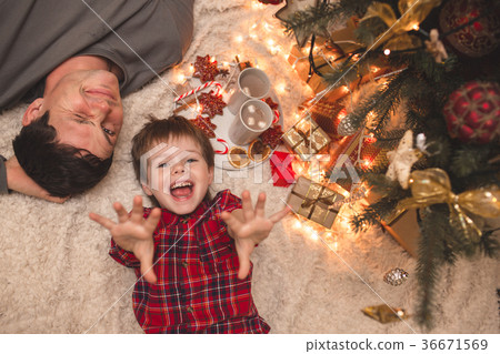 Father and son laying under christmas tree. 36671569