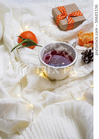 Hot Cup of tea with tangerines and sweaters on bed 36685336