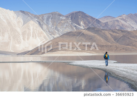 Travel man walking on the sand promontory at lake Travel man walking on the sand promontory at lake 36693923