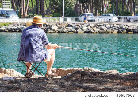 Retired senior man enjoys fishing from a pier into Retired senior man enjoys fishing from a pier into 36697608