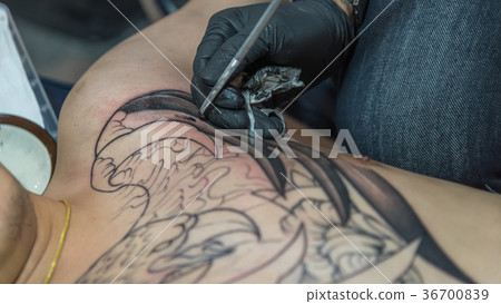 Tattoo artist drawing art on body 36700839