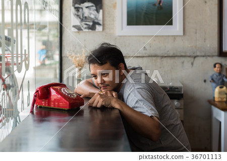 Asian man shy waiting phone call in a coffee shop Asian man shy waiting phone call in a coffee shop 36701113