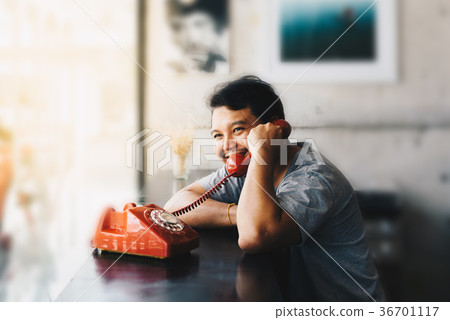 Asian man happy talking phone call in coffee shop Asian man happy talking phone call in coffee shop 36701117