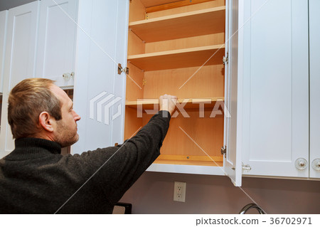 Closeup of a cabinet installer installing hardware 36702971