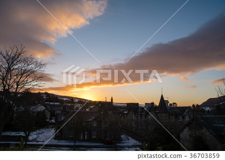The sun rising from the snow-covered town and distant view of snowy mountains outside Scotland 36703859
