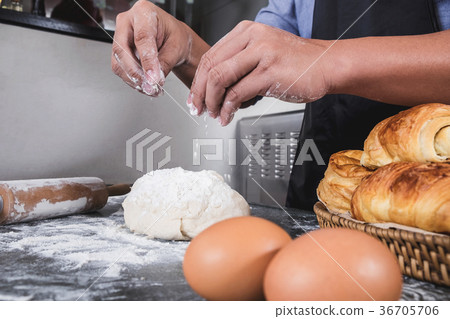 Close up of Man hands sprinkling flour over fresh dough with ing 36705706