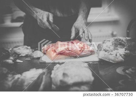 Man slicing pork meat on a table, conceptual idea 36707730