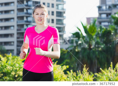 Smiling woman in pink T-shirt is jogging Smiling woman in pink T-shirt is jogging 36717952