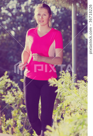 Smiling adult female in pink T-shirt is jogging 36718226