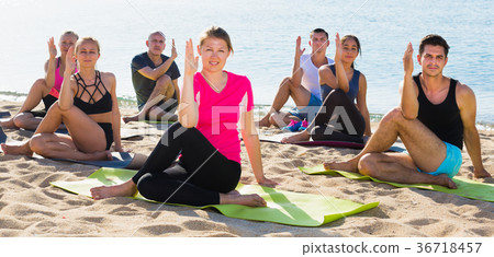 Sporty people practicing yoga on beach 36718457