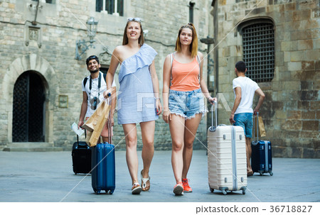two young smiling traveling girls walking together with luggage two young smiling traveling girls walking together with luggage 36718827