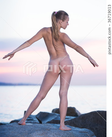 Active naked girl exercising at seaside in evening 36719013