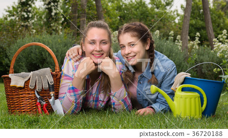 smiling young woman and girl with gardening tools in outdoors 36720188
