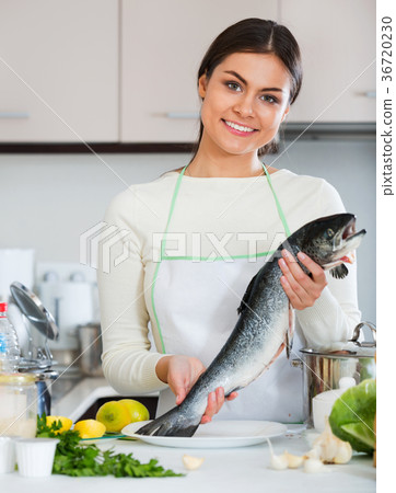 Attractive Young smiling brunette girl preparing trout dish 36720230