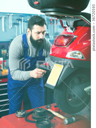 Young man worker working at restoring motorbike in workshop 36720593