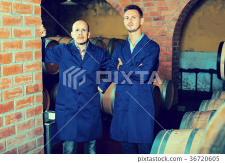 two men in uniforms standing in cellar with wine woods two men in uniforms standing in cellar with wine woods 36720605