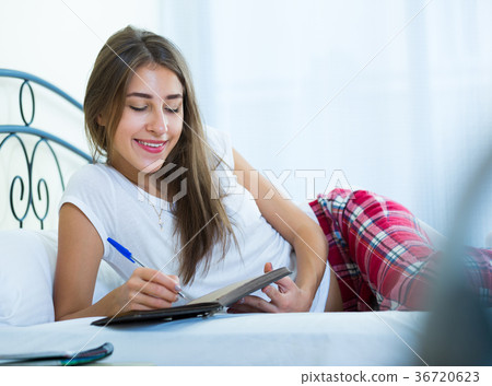 Smiling girl making shopping list in bedroom Smiling girl making shopping list in bedroom 36720623