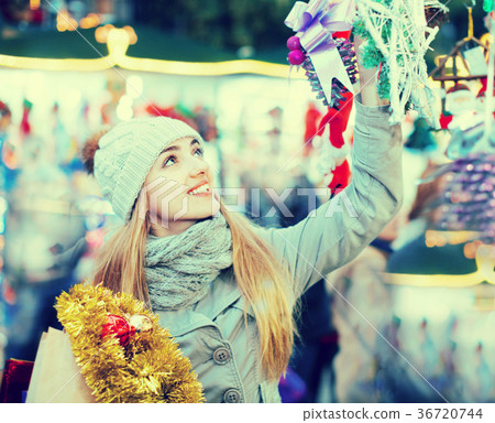 Beautiful happy woman choosing Christmas decoration at market Beautiful happy woman choosing Christmas decoration at market 36720744