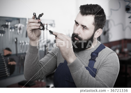 Multi-ethnic guy is observing motorbike part for fixing Multi-ethnic guy is observing motorbike part for fixing 36721336