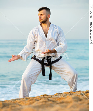 Guy doing karate poses at sunset sea shore 36721665