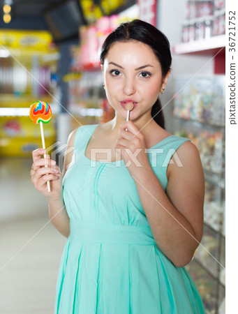 Smiling girl sucking lollypop in store 36721752
