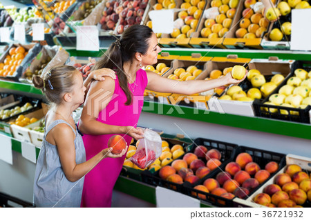 Female with daughter selecting apples in fruit section 36721932