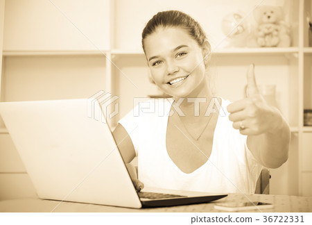 girl school pupil sitting with laptop and showing thumbs up 36722331