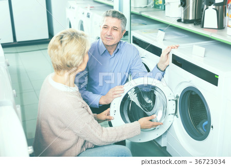 positive mature couple chooses washing machine for their house in shop of household appliances 36723034