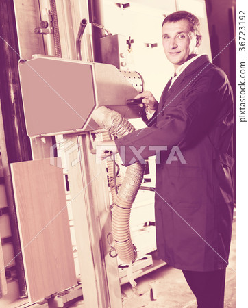 portrait of man in uniform working on large automatic saw machinery indoors portrait of man in uniform working on large automatic saw machinery indoors 36723192
