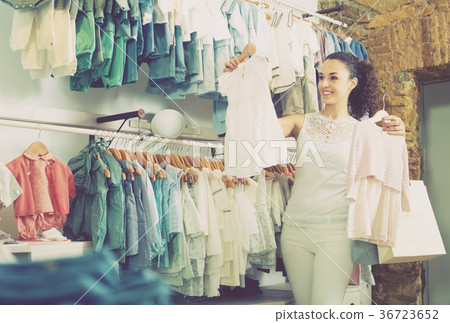 Cheerful female customer choosing baby dress 36723652