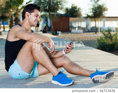 Man using smartphone during break in workout outdoors 36723830