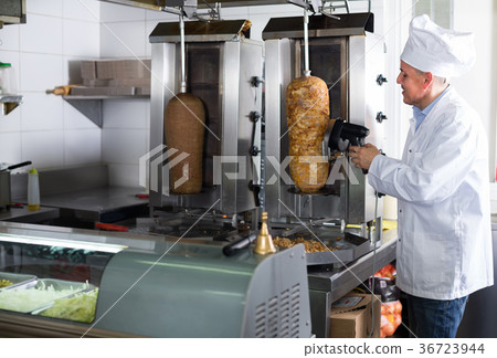 mature chef slicing kebab in fast food. mature chef slicing kebab in fast food. 36723944