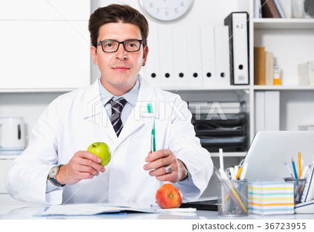 Doctor dentist in uniform demonstrating benefit of apples Doctor dentist in uniform demonstrating benefit of apples 36723955