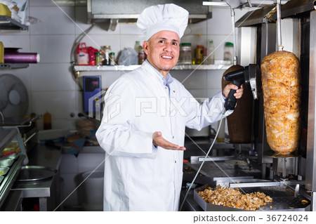 mature chef slicing kebab in fast food. mature chef slicing kebab in fast food. 36724024