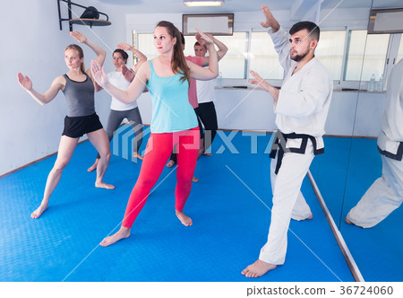 adults attempting to master new moves during karate class 36724060