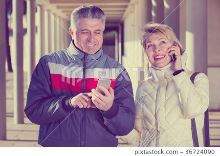 Mature married couple talking on cellular Mature married couple talking on cellular 36724090