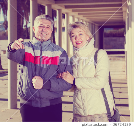 Mature couple walks outdoors and point by hand 36724189