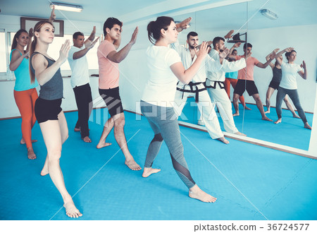 adults attempting to master new moves during karate class 36724577