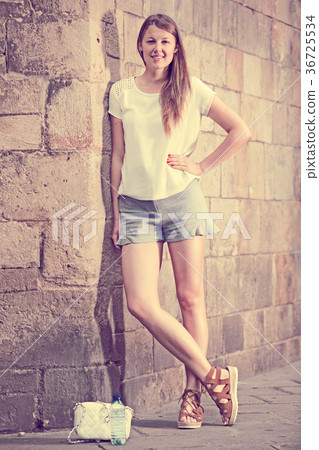 Young woman standing near old stone wall Young woman standing near old stone wall 36725534