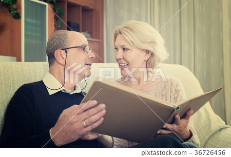 Senior spouses with picture album indoor 36726456