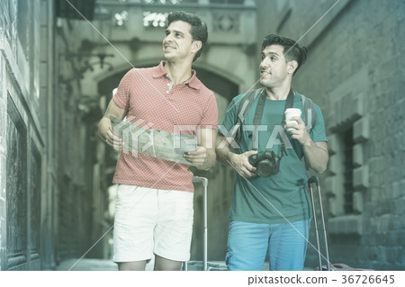 active men are walking with photocamera and searching way to historical sight in map in Barcelona active men are walking with photocamera and searching way to historical sight in map in Barcelona 36726645