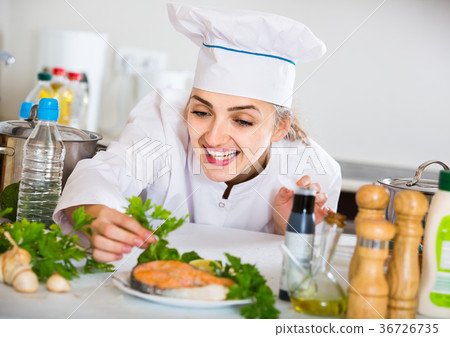 young cook with prepared salmon in professional kitchen young cook with prepared salmon in professional kitchen 36726735