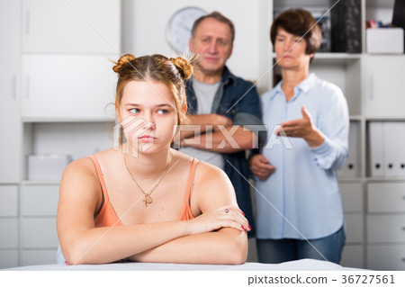 Upset female is sitting at the table and her parents are sympathying with her 36727561