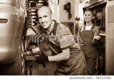 Mature male technician fitting new car tyre 36727562