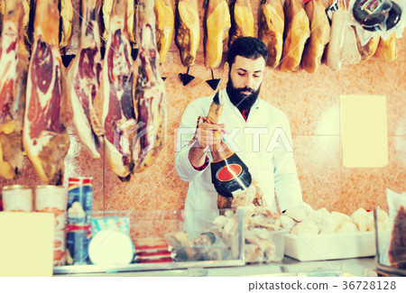 Smiling male seller showing jamon Smiling male seller showing jamon 36728128