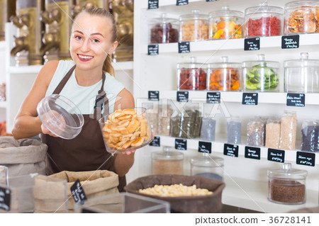 Young woman is offering dried fruits in container 36728141