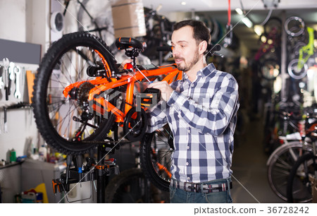 Man shows to regulate the seat to the bicycle Man shows to regulate the seat to the bicycle 36728242