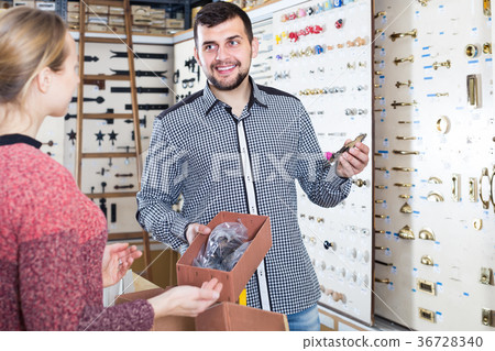 professional male seller assisting woman in choosing door handles in shop professional male seller assisting woman in choosing door handles in shop 36728340